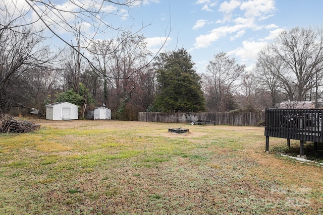 view of yard featuring a wooden deck, a storage unit, and a fire pit