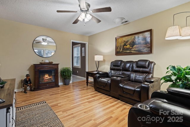 living room with ceiling fan, wood-type flooring, and a textured ceiling