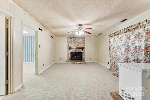 unfurnished living room featuring crown molding, light colored carpet, a brick fireplace, a textured ceiling, and ceiling fan