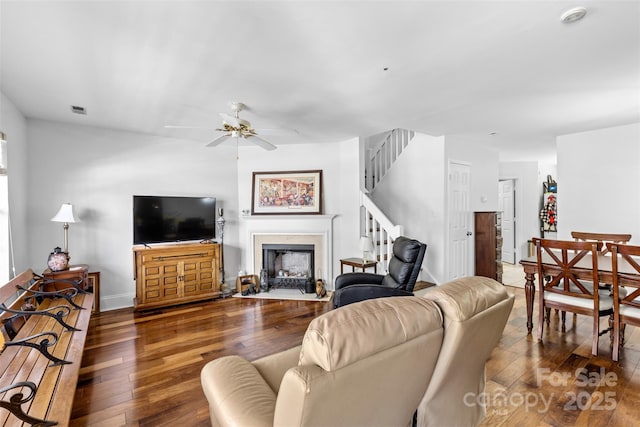 living area with visible vents, a fireplace with flush hearth, hardwood / wood-style flooring, baseboards, and stairs