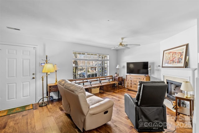 living room with visible vents, a fireplace, ceiling fan, and hardwood / wood-style flooring