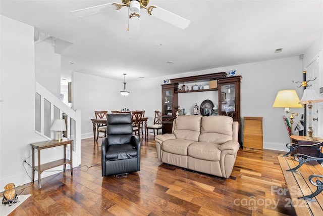 living area featuring visible vents, a ceiling fan, baseboards, and wood finished floors