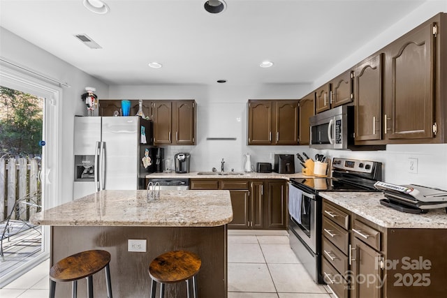 kitchen with visible vents, light tile patterned floors, decorative backsplash, stainless steel appliances, and a sink