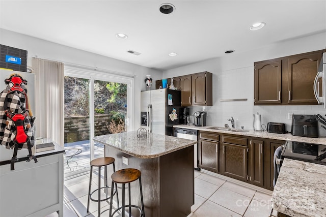 kitchen featuring visible vents, a sink, stainless steel appliances, a kitchen breakfast bar, and backsplash