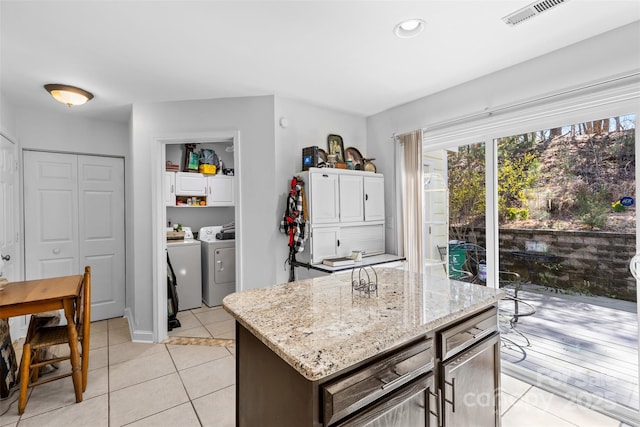 kitchen featuring light tile patterned floors, visible vents, light stone countertops, and separate washer and dryer