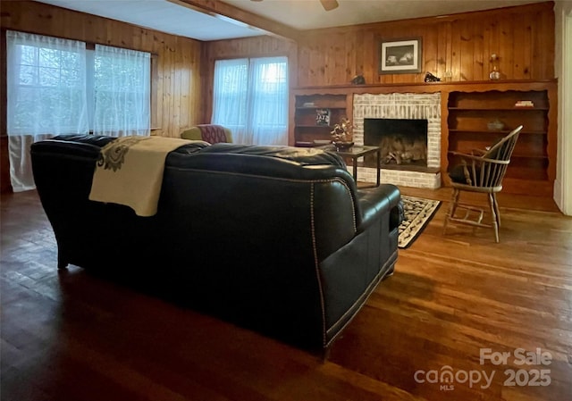 living room with ceiling fan, dark hardwood / wood-style floors, a brick fireplace, and wood walls