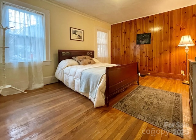 bedroom featuring crown molding, wood-type flooring, and wood walls