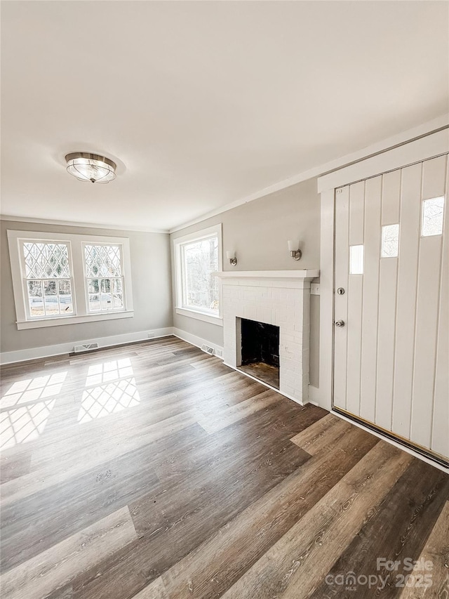 unfurnished living room featuring a fireplace, crown molding, and wood-type flooring