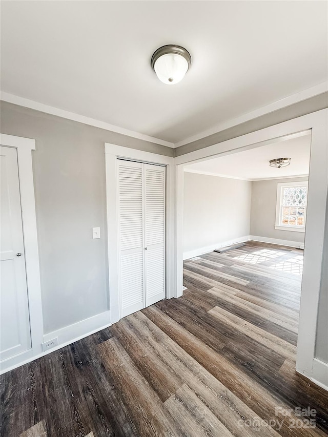 unfurnished bedroom with hardwood / wood-style flooring, ornamental molding, and a closet