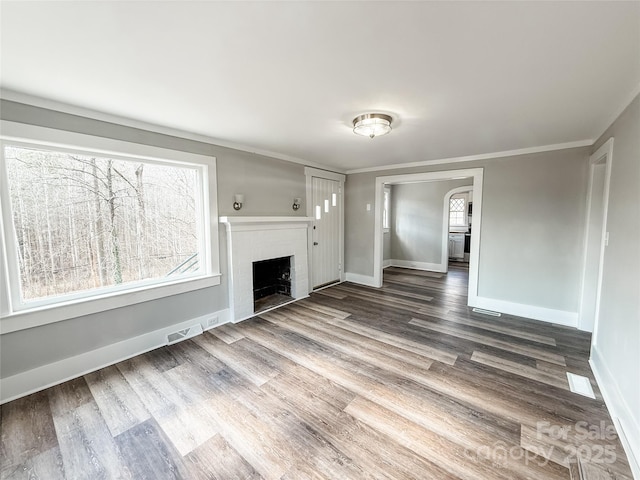 unfurnished living room featuring hardwood / wood-style flooring, plenty of natural light, and ornamental molding