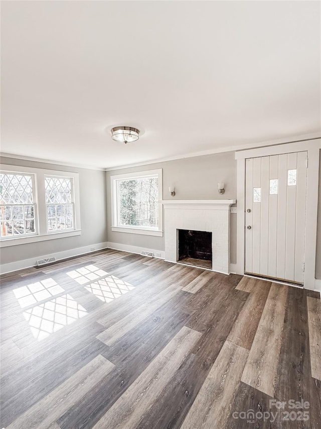 unfurnished living room with ornamental molding and wood-type flooring