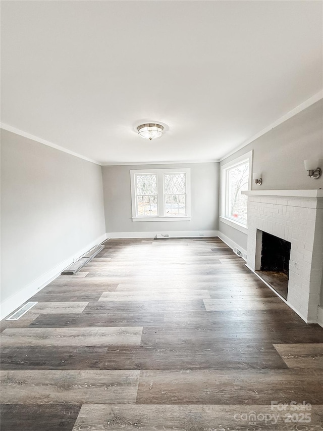 unfurnished living room featuring ornamental molding, a brick fireplace, and wood-type flooring