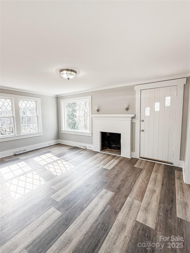 unfurnished living room featuring hardwood / wood-style flooring and ornamental molding