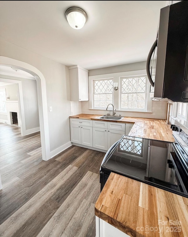 kitchen featuring butcher block counters, sink, white cabinetry, and wood-type flooring
