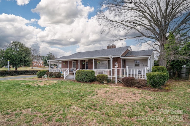 view of front of property featuring a porch, a front yard, brick siding, and a chimney