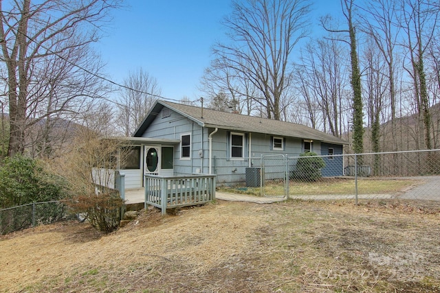 back of property with a gate, a deck, fence private yard, and a sunroom