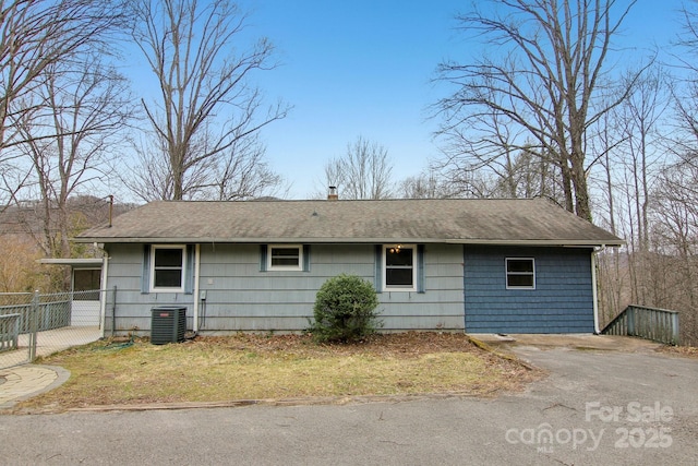 exterior space featuring a chimney, a shingled roof, central AC, and fence