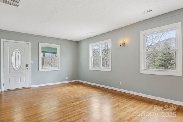 foyer entrance featuring light wood-style floors, baseboards, and visible vents