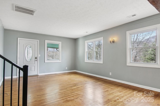 entryway with stairs, wood finished floors, visible vents, and baseboards