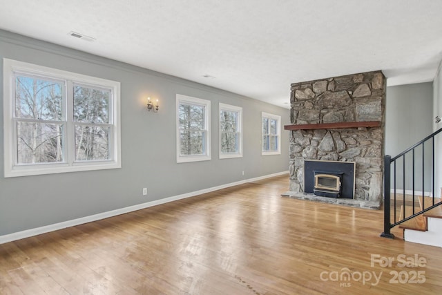 unfurnished living room with a wealth of natural light, stairs, and wood finished floors