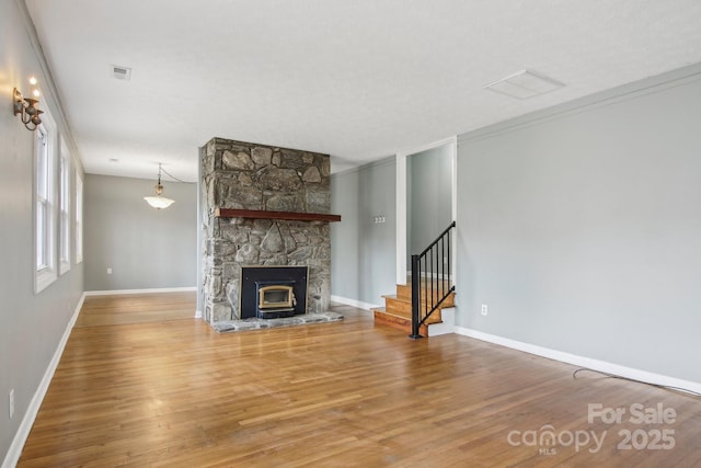 unfurnished living room with visible vents, baseboards, wood finished floors, and stairs