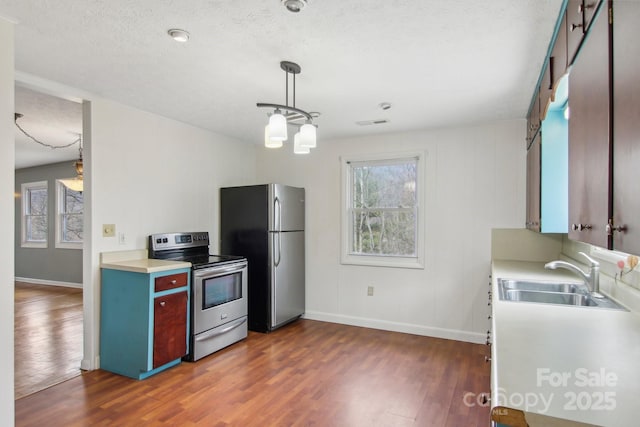 kitchen with a sink, baseboards, light countertops, appliances with stainless steel finishes, and dark wood-style flooring