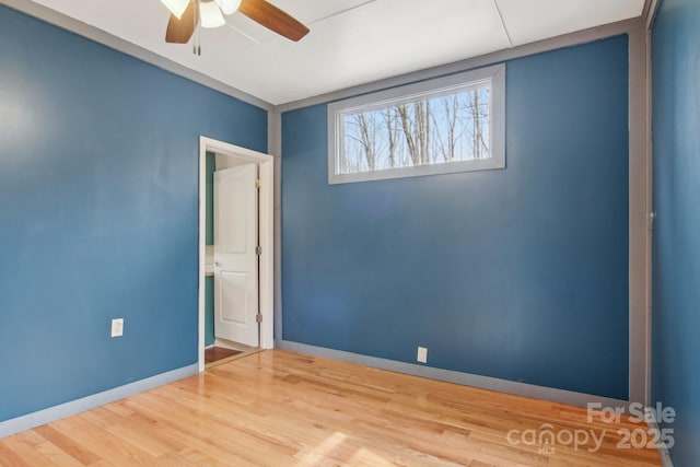 empty room featuring baseboards, wood finished floors, and a ceiling fan