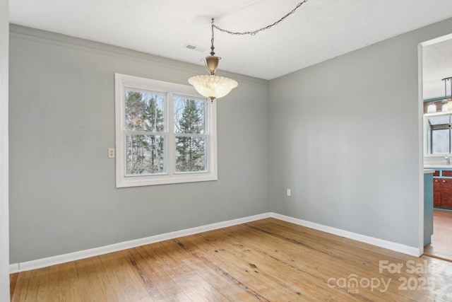 unfurnished dining area featuring hardwood / wood-style flooring, visible vents, and baseboards