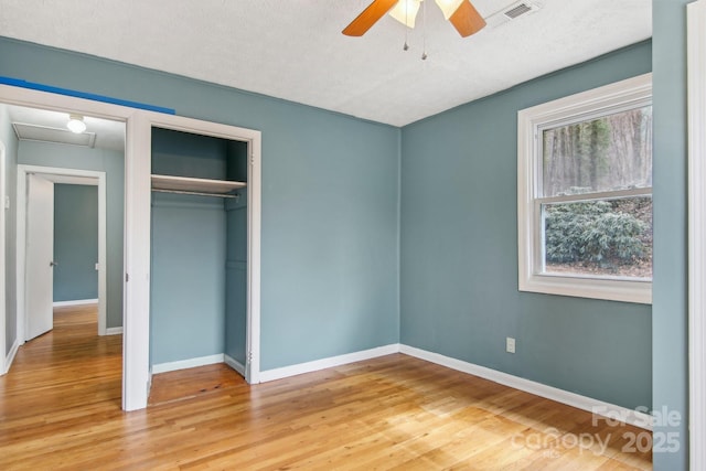 unfurnished bedroom featuring visible vents, multiple windows, and wood finished floors