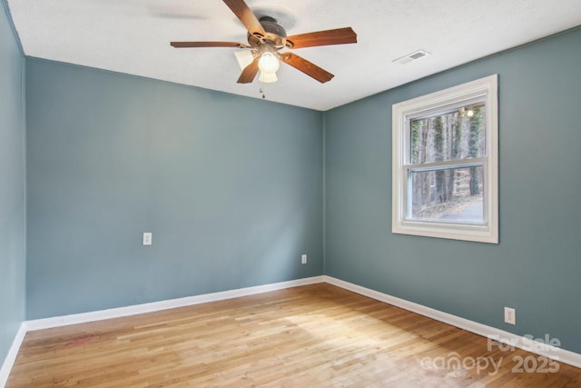 empty room with visible vents, baseboards, wood finished floors, and a ceiling fan