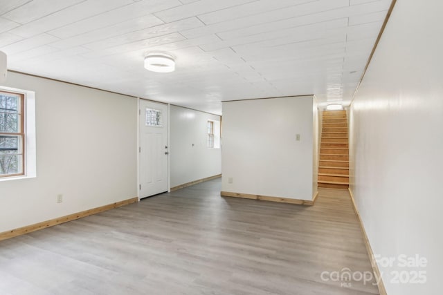 basement featuring stairs, plenty of natural light, wood finished floors, and baseboards