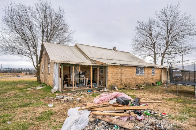 rear view of property with a trampoline