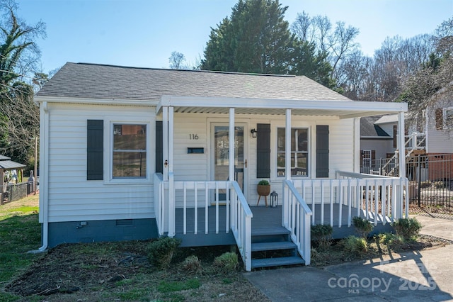 bungalow-style house featuring covered porch, a shingled roof, crawl space, and fence