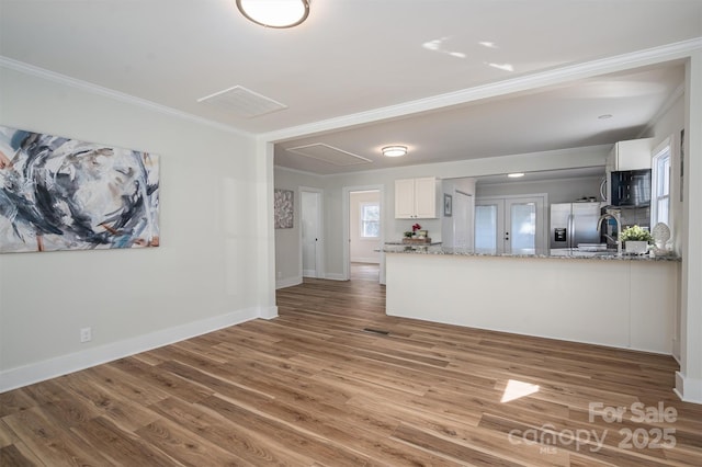 unfurnished living room with ornamental molding, baseboards, and wood finished floors