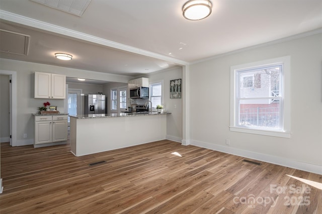 kitchen featuring a peninsula, wood finished floors, visible vents, white cabinets, and appliances with stainless steel finishes