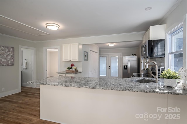 kitchen with light stone counters, dark wood-style floors, stainless steel appliances, white cabinets, and a sink