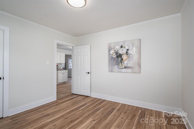 unfurnished bedroom with baseboards, ornamental molding, and wood finished floors