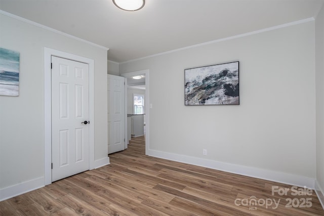 unfurnished bedroom featuring crown molding, wood finished floors, and baseboards