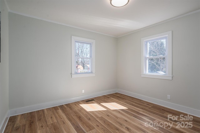 unfurnished room with a healthy amount of sunlight, crown molding, baseboards, and wood finished floors