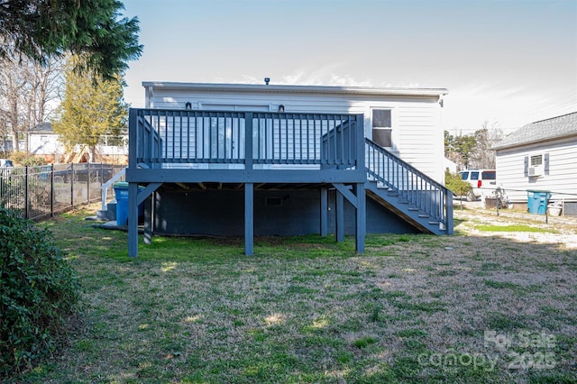 rear view of property featuring a deck, fence, a lawn, and stairs