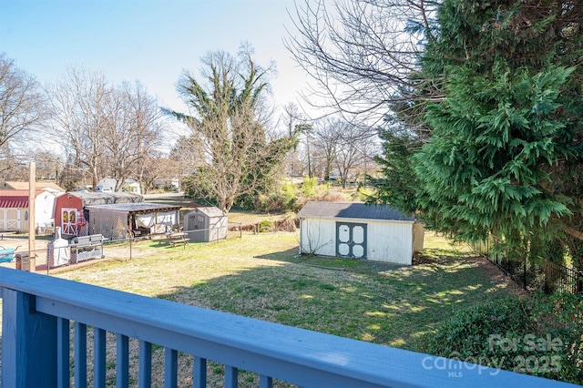 view of yard featuring a storage shed, fence, and an outdoor structure