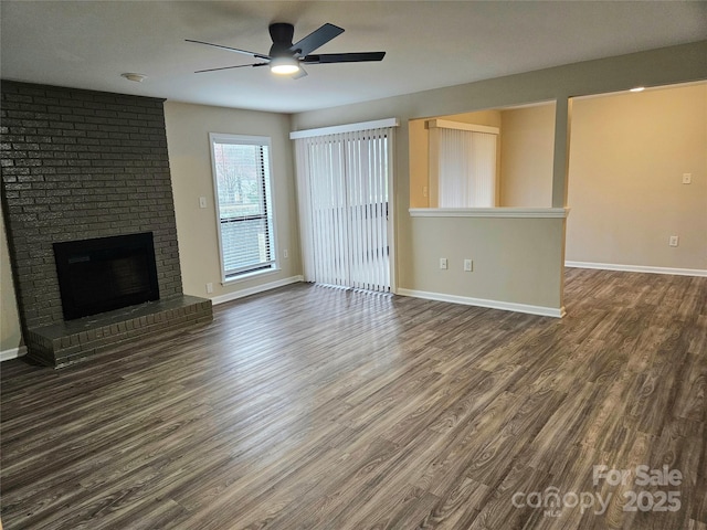 unfurnished living room with dark wood-type flooring, ceiling fan, and a brick fireplace