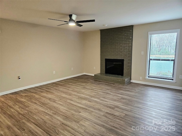 unfurnished living room featuring a fireplace, wood-type flooring, and ceiling fan