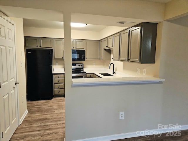 kitchen with sink, gray cabinets, black appliances, kitchen peninsula, and light wood-type flooring