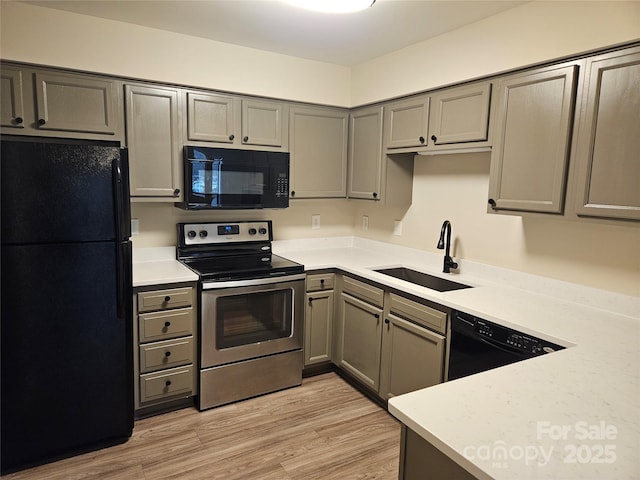 kitchen with gray cabinetry, sink, black appliances, and light wood-type flooring