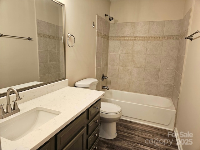 full bathroom with hardwood / wood-style flooring, tiled shower / bath, vanity, and toilet