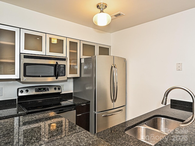 kitchen featuring appliances with stainless steel finishes, sink, and dark stone counters