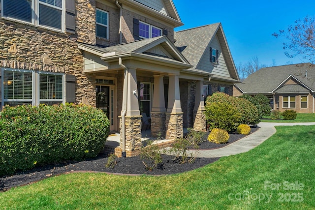 view of home's exterior with a lawn, stone siding, and roof with shingles