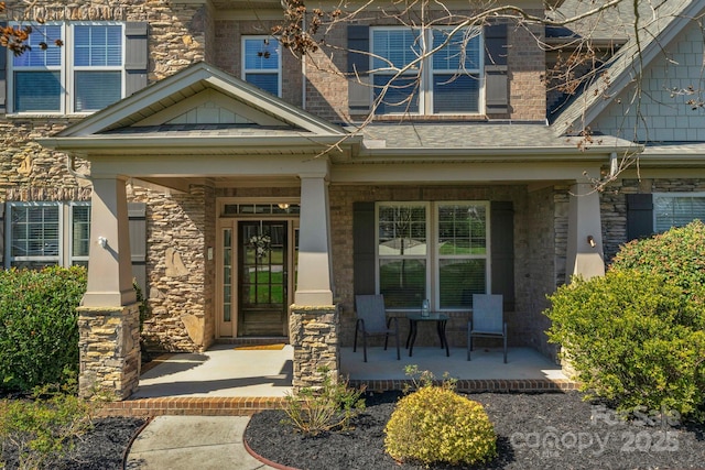 entrance to property with cooling unit, stone siding, and a porch