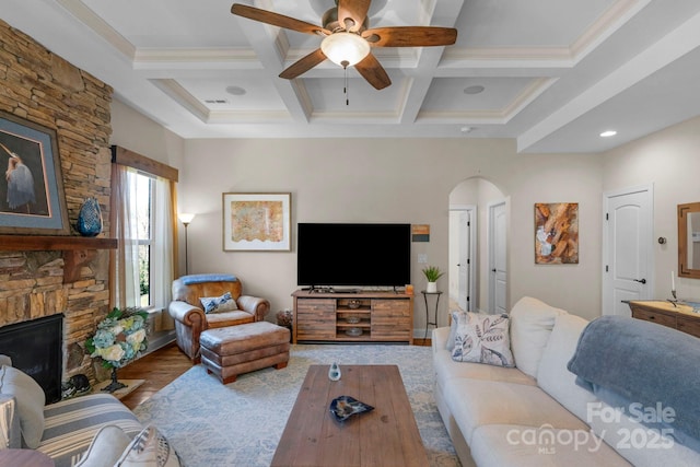 living room with beamed ceiling, a fireplace, wood finished floors, arched walkways, and coffered ceiling